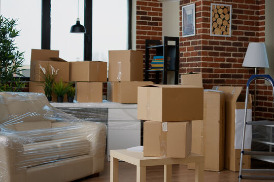 nobody-empty-living-room-with-cardboard-packaging-new-home-furniture-things-stack-carton-boxes-no-people-household-property-with-package-cargo-move-real-estate.jpg